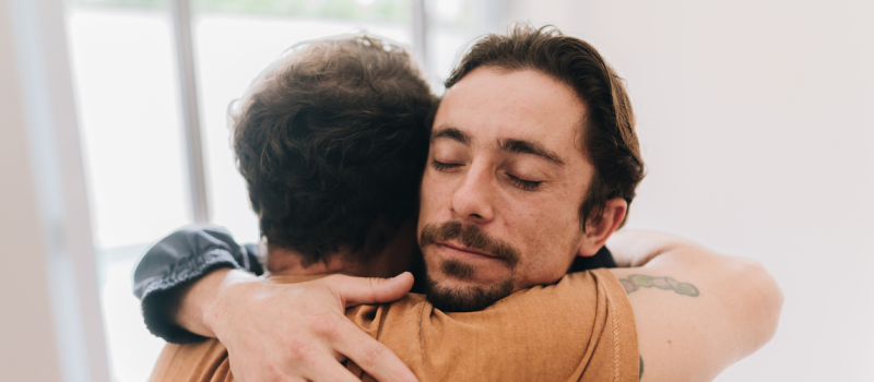 A man hugs his friend who is struggling with SUD.