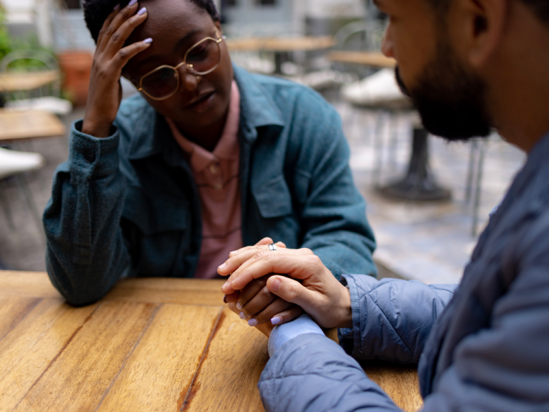 A man holds his friends hand who is currently healing from a breakup.