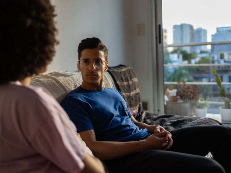 A young man is sitting with his partner who is learning how to undo a defense mechanism.