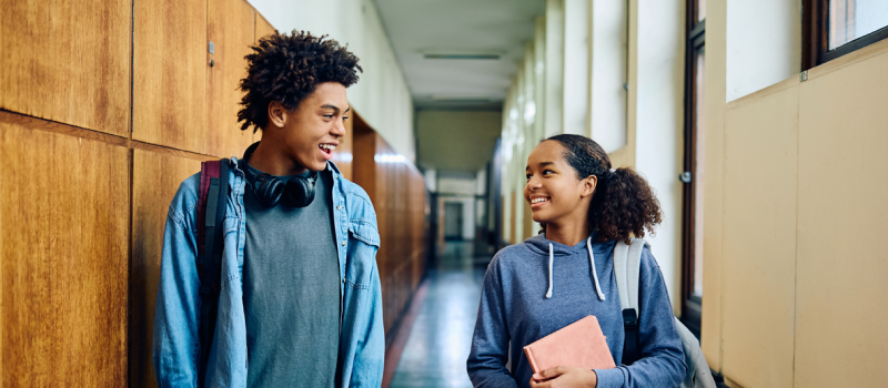 High school students walk in the hallway talking.