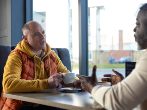 A man sits with his narcissistic friend who makes comments to manipulate him.