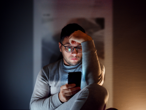 A man sits home on his phone feeling lonely.