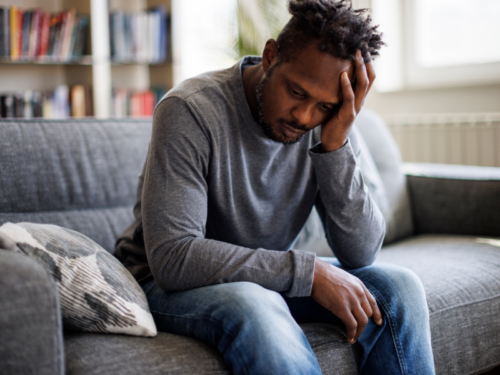 A man sits on his couch experiencing suicidal thoughts.