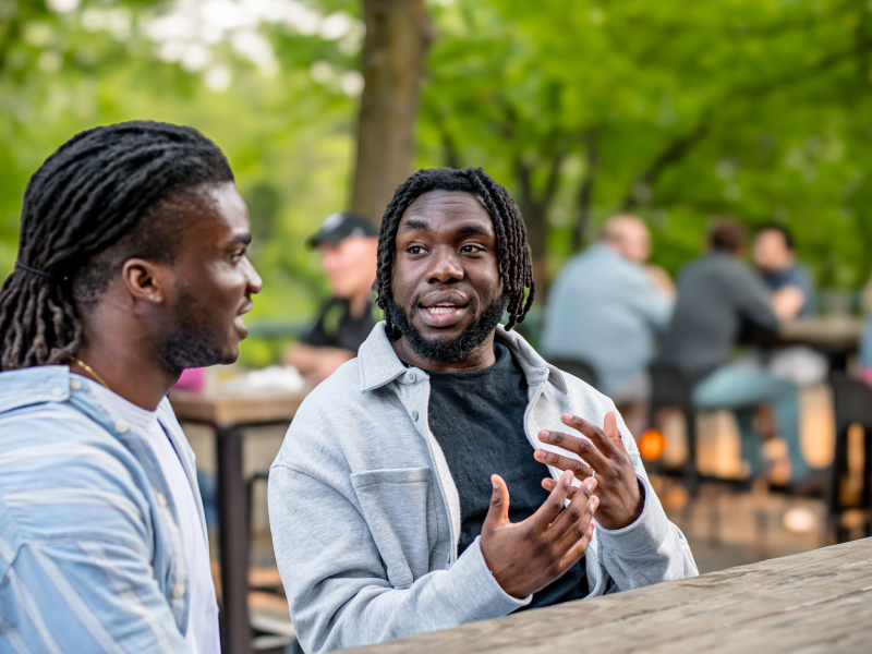 A man talks to his friend outside.