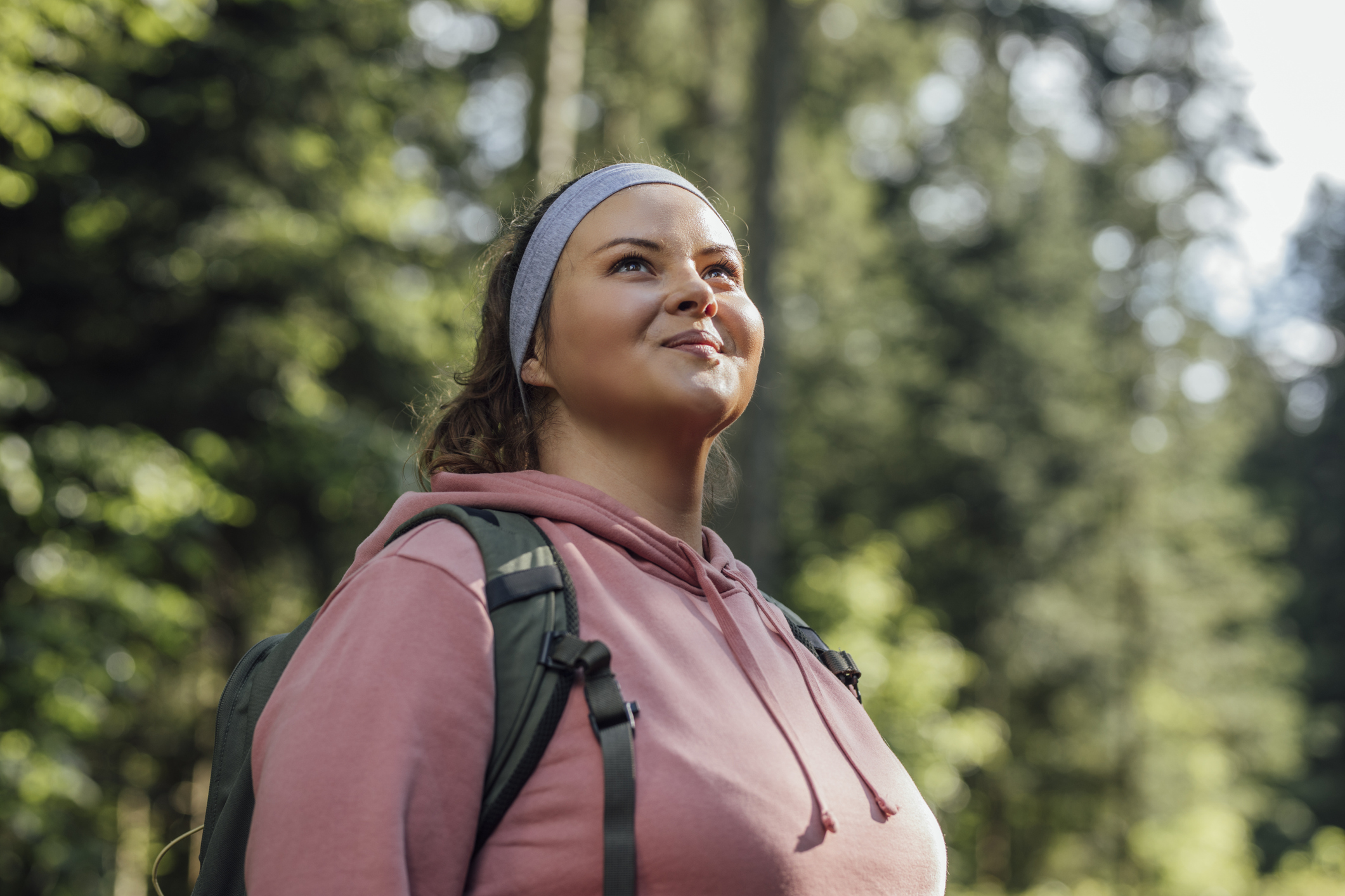 Happy woman with a backpack spending a day in nature, as she's able to try new things following her healing.