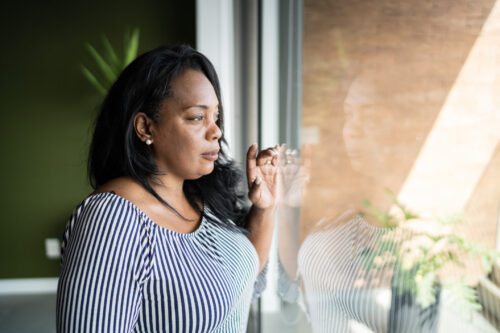 Woman contemplating at home if her Hallucinations are due to her PTSD