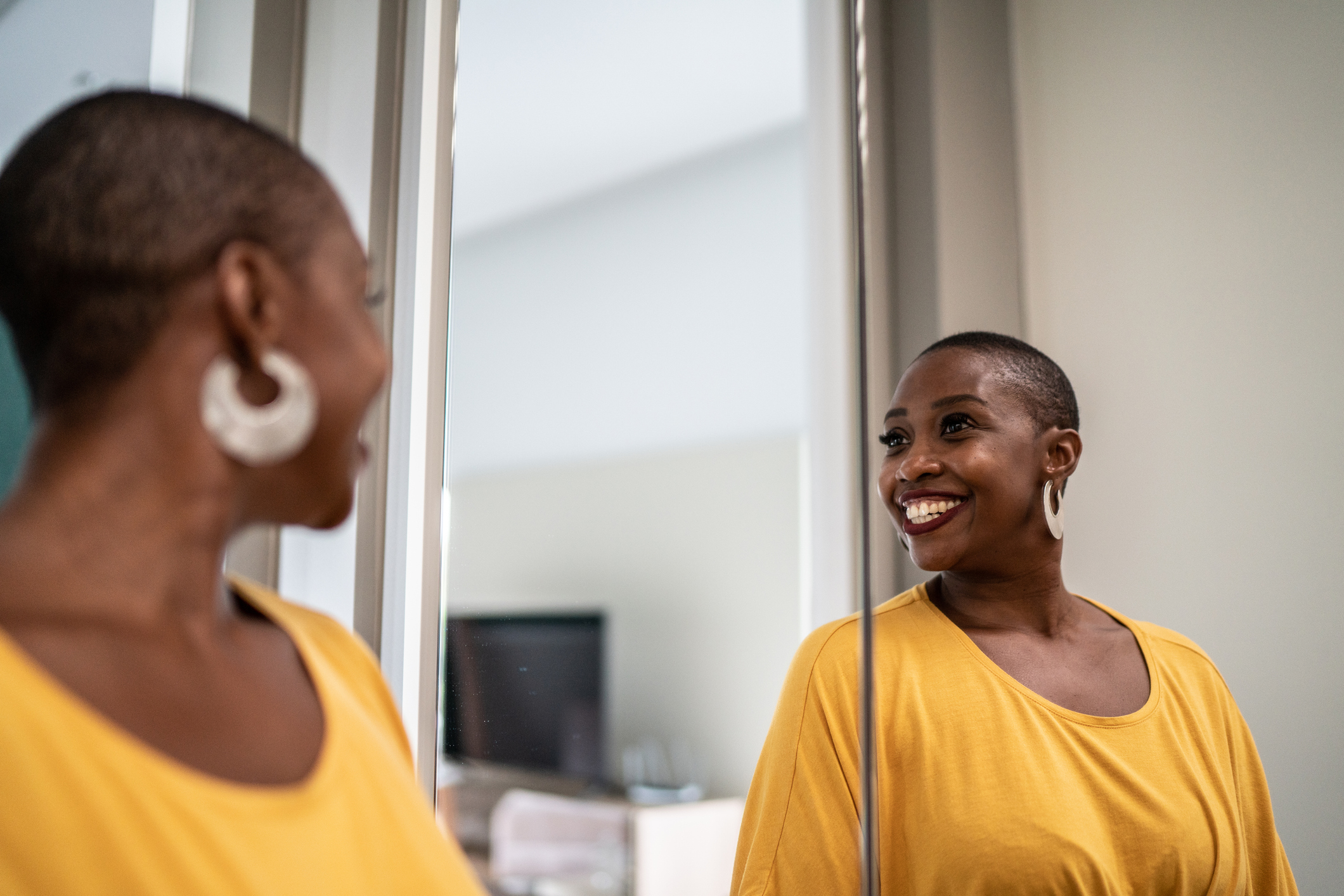 Happily seeing herself in the reflection after taking the time to get ready and take care of herself as needed