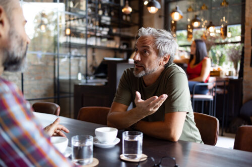 Two friends having a cup of coffee with one of them taking over the conversation with his narcissism