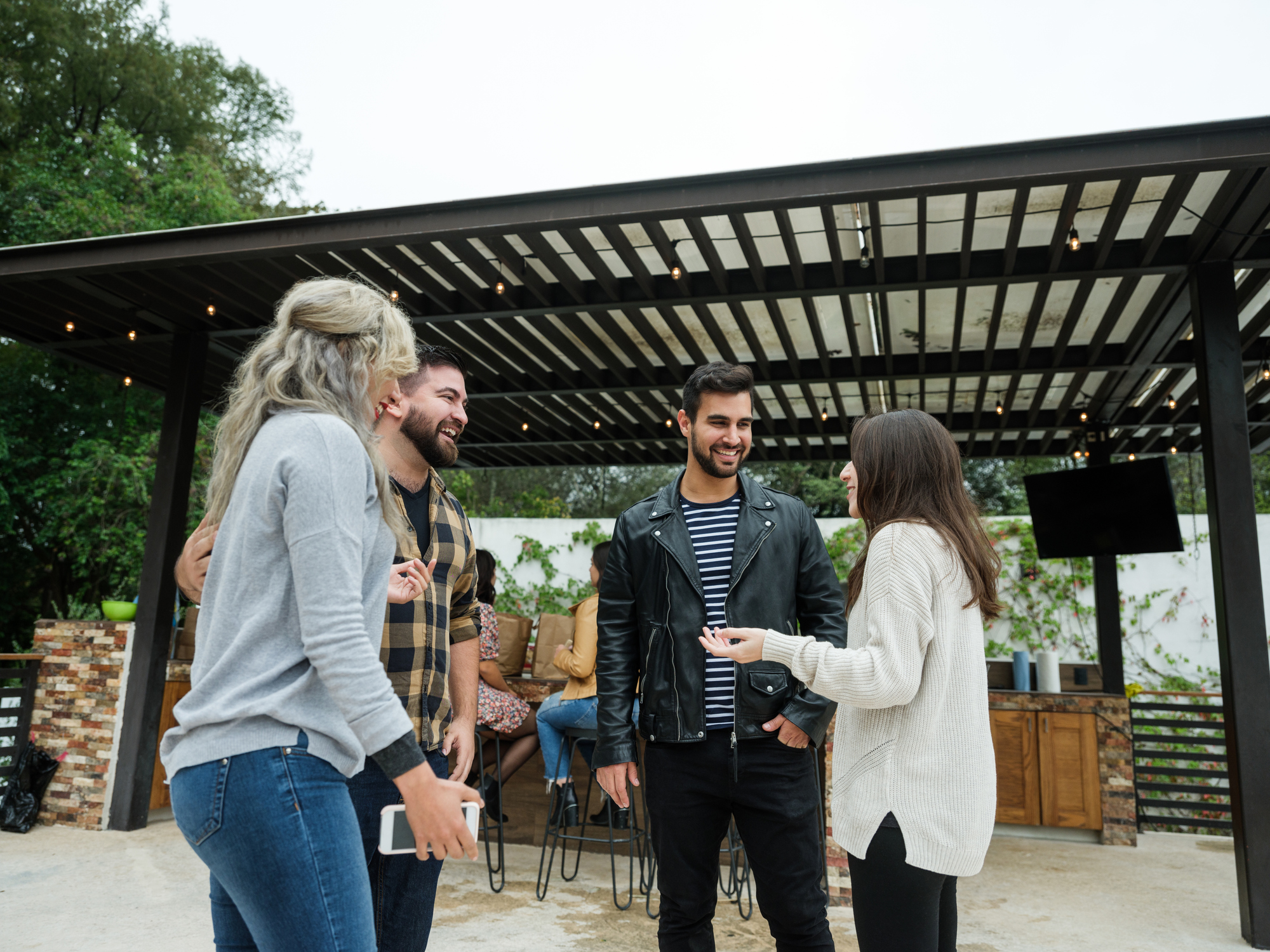 Group of friends happy to see each other, greeting and talking outside house.