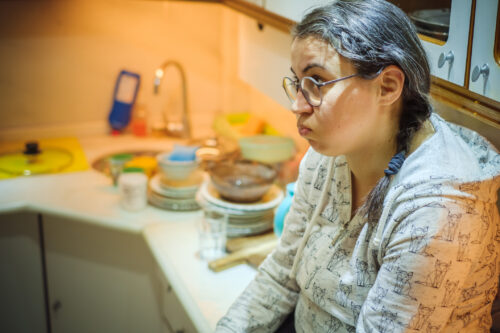 Young and frustrated woman is sitting on the kitchen counter battling her intrusive thoughts.