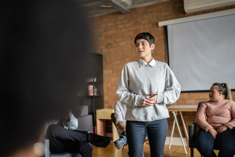 Young woman speaking to her support group about her addiction