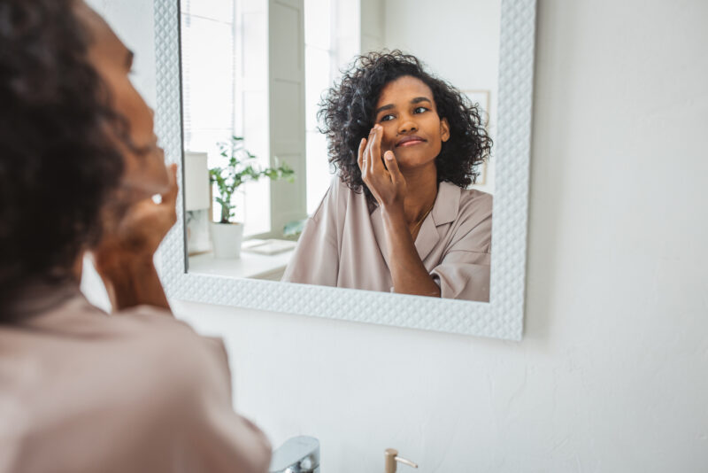 Young woman looking at herself happily in the mirror.