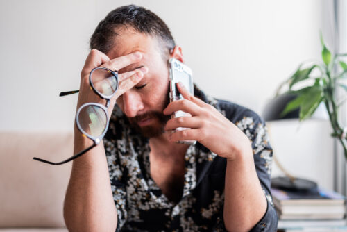 Man suffering from a headache while doing a million other things at once.